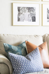 Creating a Grid Style Gallery Wall with these easy tips and tricks. Brass matted picture frames, brass swing arm sconces turned into a gallery wall creates the perfect backdrop for our sofa.