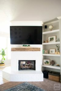 Learn how to paint a brick fireplace with this easy 3 step tutorial. Painted brick fireplace with rustic wood mantle and wall mounted tv, styled built-ins and boho outfit.