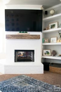 Learn how to paint a brick fireplace with this easy 3 step tutorial. Painted brick fireplace with rustic wood mantle and wall mounted tv, styled built-ins and boho outfit.