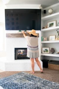 Learn how to paint a brick fireplace with this easy 3 step tutorial. Painted brick fireplace with rustic wood mantle and wall mounted tv, styled built-ins and boho outfit.