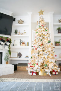 A snowy flocked Christmas tree decorated in red, green and gold gives a big dose of nostalgia to this modern farmhouse living room. 