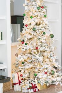 A snowy flocked Christmas tree decorated in red, green and gold gives a big dose of nostalgia to this modern farmhouse living room. 