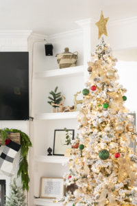 A snowy flocked Christmas tree decorated in red, green and gold gives a big dose of nostalgia to this modern farmhouse living room. 