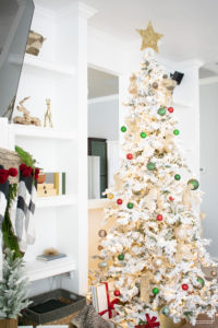 A snowy flocked Christmas tree decorated in red, green and gold gives a big dose of nostalgia to this modern farmhouse living room. 