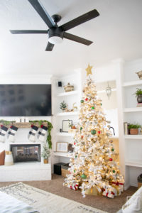 A snowy flocked Christmas tree decorated in red, green and gold gives a big dose of nostalgia to this modern farmhouse living room. 