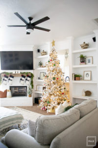 A snowy flocked Christmas tree decorated in red, green and gold gives a big dose of nostalgia to this modern farmhouse living room. 