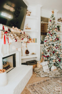 Warm and Cozy Christmas tree with pink, burgundy and gold ornaments, black and white stripe ribbon, satin burgundy ribbon tied in bows, brass tree collar, glittered magnolia leaves, faux fur west elm throw blanket and white + gold Christmas gifts add the perfect touch to these custom living room built-ins.