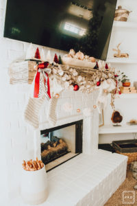 Warm and Cozy Christmas tree with pink, burgundy and gold ornaments, black and white stripe ribbon, satin burgundy ribbon tied in bows, brass tree collar, glittered magnolia leaves, faux fur west elm throw blanket and white + gold Christmas gifts add the perfect touch to these custom living room built-ins.