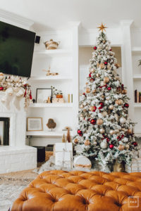 Warm and Cozy Christmas tree with pink, burgundy and gold ornaments, black and white stripe ribbon, satin burgundy ribbon tied in bows, brass tree collar, glittered magnolia leaves, faux fur west elm throw blanket and white + gold Christmas gifts add the perfect touch to these custom living room built-ins.