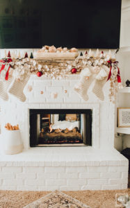 Warm and Cozy Christmas tree with pink, burgundy and gold ornaments, black and white stripe ribbon, satin burgundy ribbon tied in bows, brass tree collar, glittered magnolia leaves, faux fur west elm throw blanket and white + gold Christmas gifts add the perfect touch to these custom living room built-ins.