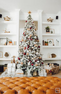 Warm and Cozy Christmas tree with pink, burgundy and gold ornaments, black and white stripe ribbon, satin burgundy ribbon tied in bows, brass tree collar, glittered magnolia leaves, faux fur west elm throw blanket and white + gold Christmas gifts add the perfect touch to these custom living room built-ins.